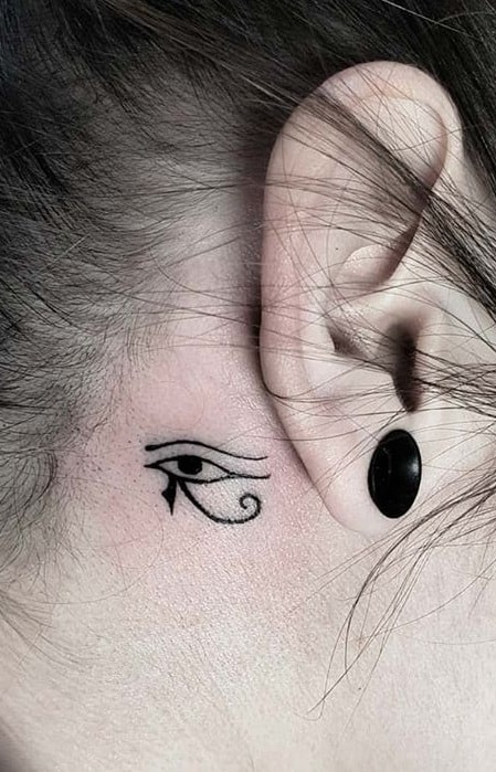 Pequeño tatuaje del ojo de Horus detrás de la oreja