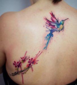 Tatuaje de colibrí acuarela con flor