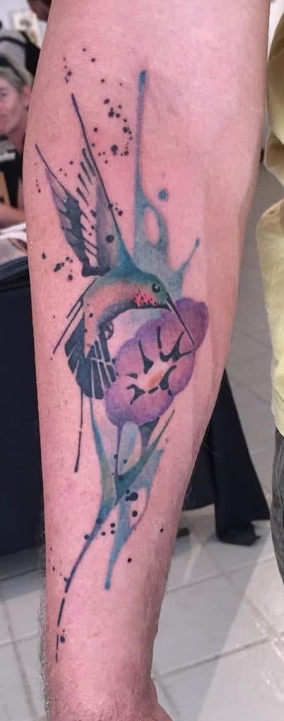 Tatuaje de colibrí acuarela con flor