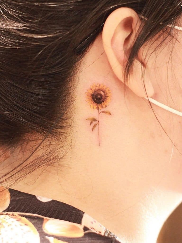 Pequeño tatuaje de girasol detrás de la oreja