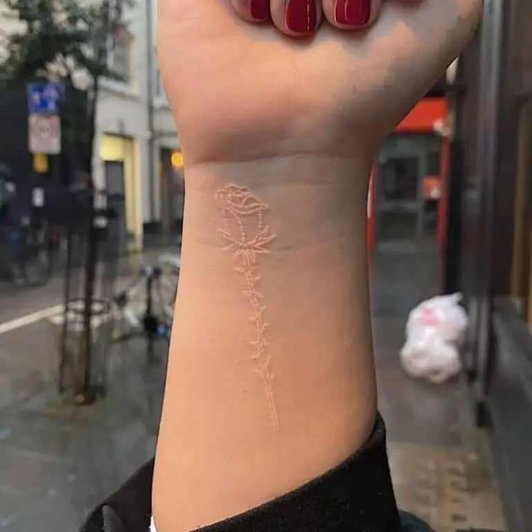 tatuaje de flor de tinta blanca en la mano de la mujer